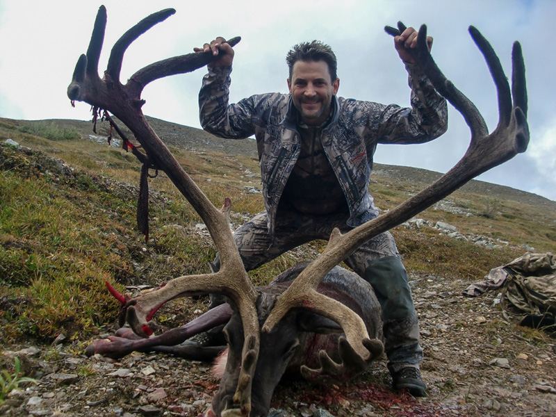 Large caribou with hunter holding antlers